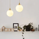 Minimalist brass pendant light with milky glass orb